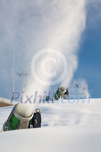 Snow-machine bursting artificial snow over a skiing slope to alow for the skiing season to start Snow-machine bursting artificial snow over a skiing slope to alow for the skiing season to start