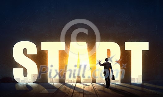 Back view of businessman standing in light of word start Back view of businessman standing in light of word start