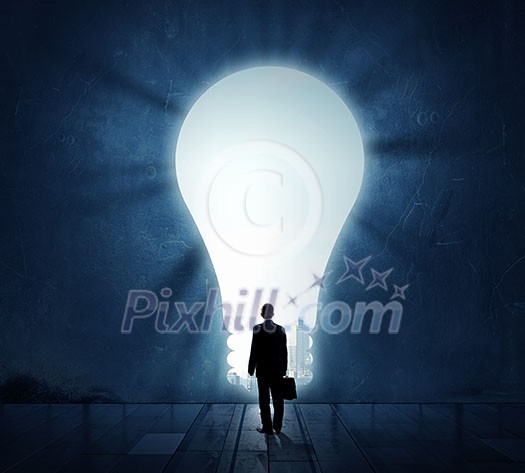 Back view of businessman standing in light of idea concept Back view of businessman standing in light of idea concept