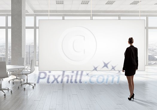 Elegant businesswoman in modern office interior against window panoramic view looking at blank banner Elegant businesswoman in modern office interior against window panoramic view looking at blank banner