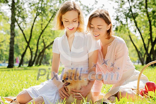 Two pretty ladies in park with their cute pet Two pretty ladies in park with their cute pet