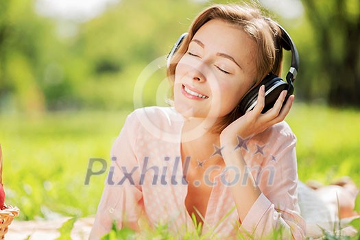 Young pretty lady in park listening to music