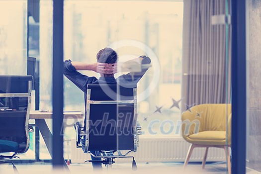 A time for relax. Young tired casual businessman relaxing at the desk in his office A time for relax. Young tired casual businessman relaxing at the desk in his office