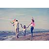 young family with kids resting and having fun with a kite at beach during autumn day