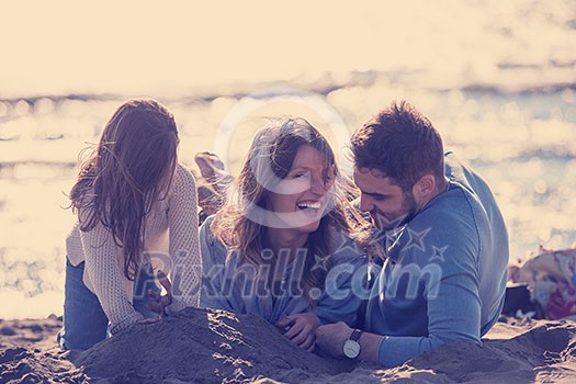 Family with kids resting and having fun at beach during autumn day