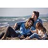Family with kids resting and having fun at beach during autumn day