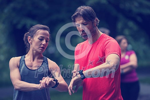 Young sporty couple using smart watches starting their timer before jogging Young sporty couple using smart watches starting their timer before jogging