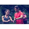 Young sporty couple using smart watches starting their timer before jogging