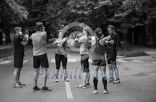 healthy runners team warming up and stretching in city park before morning training healthy runners team warming up and stretching in city park before morning training