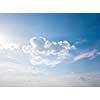 White fluffy clouds and bright sunshine on a blue sky. Concept of summer background