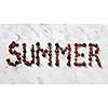 Word SUMMER made ripe sweet juicy red berries on gray stone background. Summer concept of healthy organic rood. Flat lay.