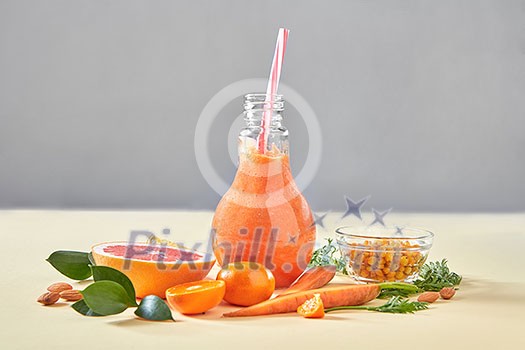 Vegetarian colorful orange cocktail from organic vegetables, fruits and berries on a paper background with copy space. Concept of natural organic healthy food. Vegetarian colorful orange cocktail from organic vegetables, fruits and berries on a paper background with copy space. Concept of natural organic healthy food.