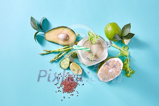 Homemade green smoothies with green vegetables and fruits, slices of lemon, lime and flax seeds on a blue paper background. Vegan and healthy eating. Homemade green smoothies with green vegetables and fruits, slices of lemon, lime and flax seeds on a blue paper background. Vegan and healthy eating.
