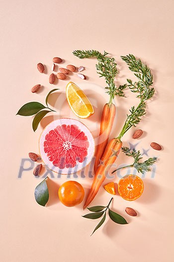 Carrot, slices of orange and grapefruit, almond, mandarins, green leaf - on a paper background. Concept of colorful organic food. Flat lay Carrot, slices of orange and grapefruit, almond, mandarins, green leaf - on a paper background. Concept of colorful organic food. Flat lay