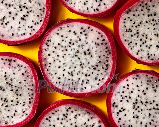 Top view of tropical exotic cut round slices of Dragon fruit or Pitaya on a yellow background. Close-up view. Top view of tropical exotic cut round slices of Dragon fruit or Pitaya on a yellow background. Close-up view.
