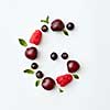 Letter G english alphabet in the form of a pattern of natural organic berries - ripe fresh raspberry, black currant, cherry, green mint leaf isolated on a white background. Flat lay