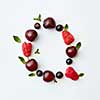 Letter Q english alphabet in the form of a pattern of natural organic berries - ripe fresh raspberry, black currant, cherry, green mint leaf isolated on a white background. Top view.