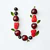 Letter U english alphabet in the form of a pattern of natural organic berries - ripe fresh raspberry, black currant, cherry, green mint leaf isolated on a white background. Top view.