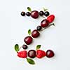 Letter Z english alphabet in the form of a pattern of natural organic berries - ripe fresh raspberry, black currant, cherry, green mint leaf isolated on a white background. Top view.