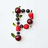 Letter P english alphabet in the form of a pattern of natural organic berries - ripe fresh raspberry, black currant, cherry, green mint leaf isolated on a white background. Top view.