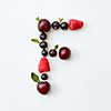 Letter F english alphabet in the form of a pattern of natural organic berries - ripe fresh raspberry, black currant, cherry, green mint leaf isolated on a white background. Top view.
