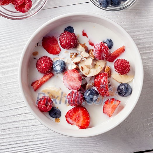 Close-up of a white ceramic bowl on a white table with natural organic ingredients for natural healthy breakfast. Concept of natural clean eating. Flat lay. Close-up of a white ceramic bowl on a white table with natural organic ingredients for natural healthy breakfast. Concept of natural clean eating. Flat lay.