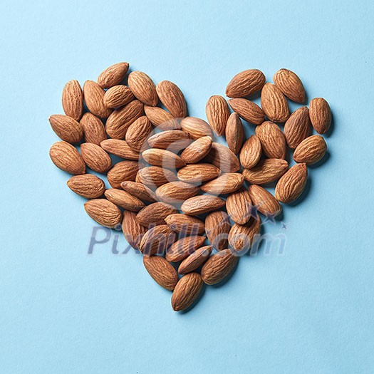 Dried almonds in the shape of heart on a blue paper background flat lay. Organic food Dried almonds in the shape of heart on a blue paper background flat lay. Organic food