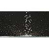 Running water falls from above on a flat surface with splashes and droplets of water, scattering in different directions against a black background. Slow motion. Full HD video, 240fps, 1080p