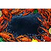 Fresh boiled crawfish with lemons and greens on a dark table with ice. Copyspace for text. Top view.