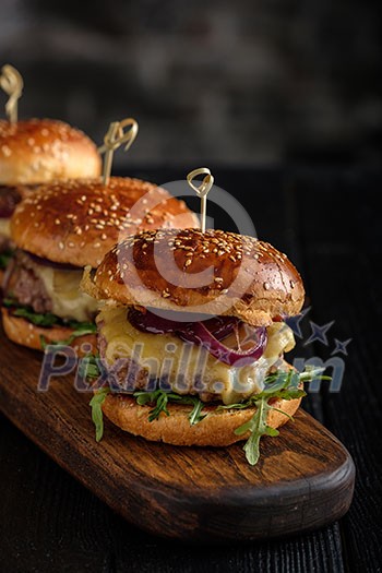 Homemade juicy burgers with beef, cheese and caramelized onions on the wooden table. Street food, fast food. Homemade juicy burgers with beef, cheese and caramelized onions on the wooden table. Street food, fast food.