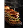 Homemade juicy burgers with beef, cheese and caramelized onions on the wooden table. Street food, fast food.