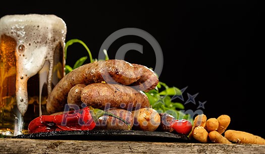 Grilled sausages with a glass of beer on a wooden table. Rustic style. Snacks for the Oktoberfest. Grilled sausages with a glass of beer on a wooden table. Rustic style. Snacks for the Oktoberfest.