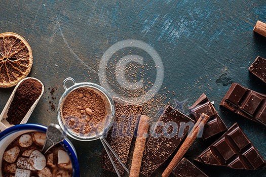 Dark and milk chocolate bars with dry orange slices, cinnamon sticks and coffee beans on blue background. Copyspace. Dark and milk chocolate bars with dry orange slices, cinnamon sticks and coffee beans on blue background. Copyspace.