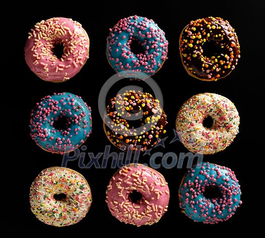 Variety of colorful tasty glazed donuts on a black background. Variety of colorful tasty glazed donuts on a black background.