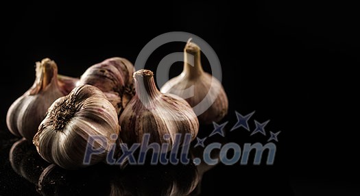 Fresh Garlic. Garlic bulbs on a black background. Place for text on the right. Copyspace. Fresh Garlic. Garlic bulbs on a black background. Place for text on the right. Copyspace.