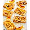 Tasty fresh homemade puff pastry with peach and honey on the white wooden table.