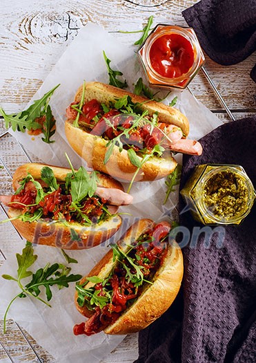Delicious fresh hot dogs in homemade buns with arugula and ketchup on a wooden background Delicious fresh hot dogs in homemade buns with arugula and ketchup on a wooden background