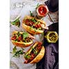 Delicious fresh hot dogs in homemade buns with arugula and ketchup on a wooden background