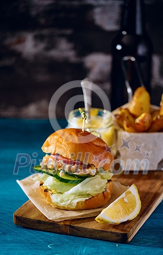 Fishburger with toppings and fries. Rustic style. Fishburger with toppings and fries. Rustic style.