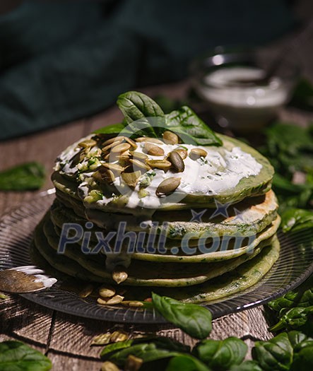 Pancakes with spinach and pumpkin seeds on a wooden table. Country style. Pancakes with spinach and pumpkin seeds on a wooden table. Country style.