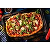 Pizza with prosciutto, mozzarella, mushroom and rocket salad with spices on blue background