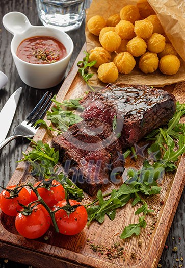 Juicy tasty grilled fillet steak served with tomatoes and cheese balls on an old wooden board Juicy tasty grilled fillet steak served with tomatoes and cheese balls on an old wooden board