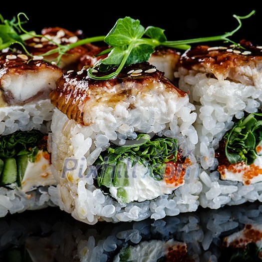 Close-up of traditional japanese sushi on a dark background with reflection. Fish Eel with Philadelphia cheese and red caviar Close-up of traditional japanese sushi on a dark background with reflection. Fish Eel with Philadelphia cheese and red caviar