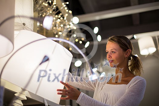 Pretty, young woman choosing the right light for her apartment in a modern home furnishings store (color toned image; shallow DOF) Pretty, young woman choosing the right light for her apartment in a modern home furnishings store (color toned image; shallow DOF)