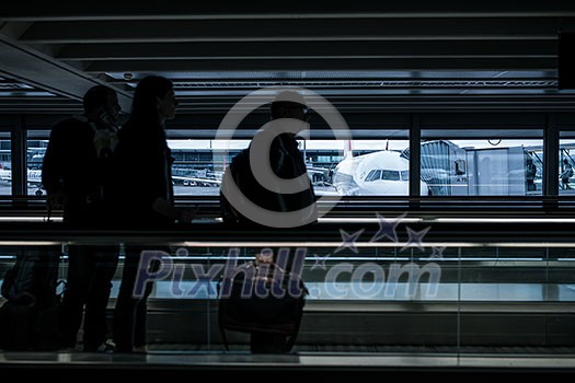 Airport rush: people with their suitcases walking along a corridor (motion blurred image; color toned image) Airport rush: people with their suitcases walking along a corridor (motion blurred image; color toned image)