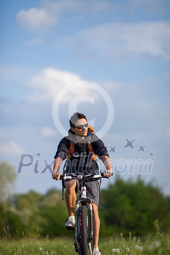 Handsome young man biking in the countryside Handsome young man biking in the countryside