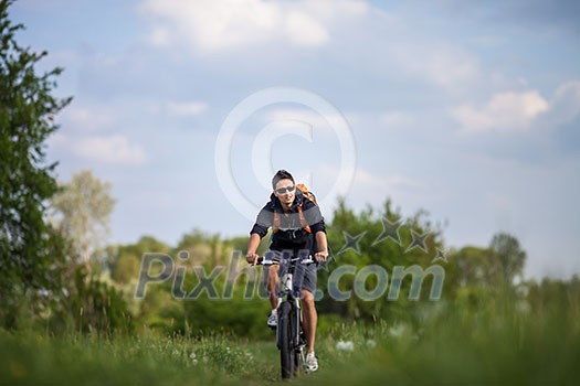 Handsome young man biking in the countryside Handsome young man biking in the countryside