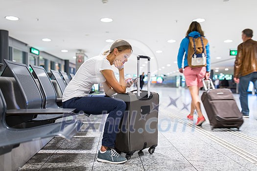 Young female passenger at the airport, using her tablet computer while waiting for her flight (color toned image) Young female passenger at the airport, using her tablet computer while waiting for her flight (color toned image)