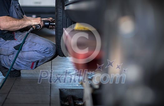 Wheel change - balancing/repairing wheels on a modern car in a garage/auto service by a mechanic Wheel change - balancing/repairing wheels on a modern car in a garage/auto service by a mechanic