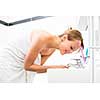 Pretty female brushing her teeth in front of mirror in the morning